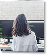Rear View Of Female Computer Hacker Coding At Desk In Creative Office Metal Print