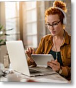 Redhead Businesswoman With Headphones Working On Touchpad In The Office. Metal Print