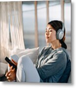 Relaxed Young Asian Woman With Eyes Closed Sitting On Her Bed Enjoying Music Over Headphones From Smartphone At Home Metal Print