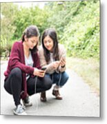 Teenaged Eurasian Sisters Playing Augmented Reality Games On Smartphones Metal Print