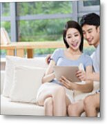 Young Couple Using Digital Tablet On Sofa Metal Print