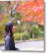 Young Woman Looking At Orange Autumn Leaves In Public Park Metal Print