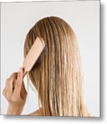 Young Woman With Comb Brushing Her Wet, Blonde, Perfect Hair After Shower On The Gray Background. Care About Beautiful, Healthy And Clean Hair. Beauty Salon Concept. Back View. Metal Print