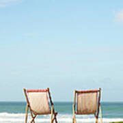 Deck Chairs On Coastline Facing Out To Poster