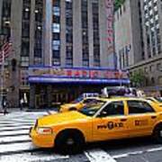 Yellow Cabs Pass In Front Of Radio City Music Hall Poster