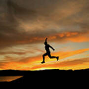 Silhouette Of Man Jumping With Cap In The Sunset #1 Poster