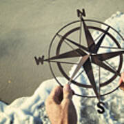 Hands Holding Compass Over Waves Rushing On Beach Art Print