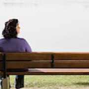 Rear View Of Overweight Woman Sitting On Park Bench Near Lake Wood