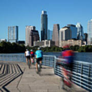 A Group Of Cyclists Ride Down The Boardwalk Trail Which Offers Stunning Views Of The Austin Skyline Art Print