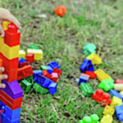 Child Playing With Colorful Blocks Sitting On The Ground Of A Garden In Spring, Negative Space. Art Print