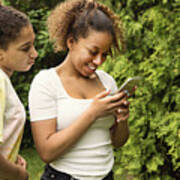 Mixed-race Teenage Sisters Looking At Mobile Phone In Backyard. #1 Art Print