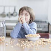 Boy Eating Bowl Of Cereal In Kitchen Art Print