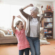 Caucasian Grandmother And Granddaughter Dancing In Living Room Art Print