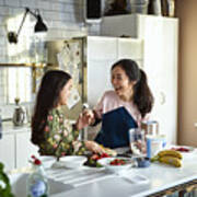 Mother Teasing Daughter In Kitchen Whilst Making Smoothies Art Print