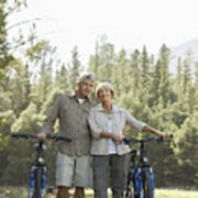 Senior Couple Standing Side By Side With Their Bikes With Woodland In The Background Art Print