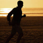 Silhouette Of A Tall Man Running On Beach At Sunset Stock Photo Art Print