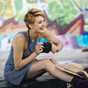 Stylish Teenage Girl Sitting On Sidewalk With Camera In Front Of Graffiti Wall Art Print