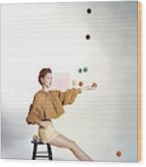 A Model Sitting On A Stool Juggling Wood Print