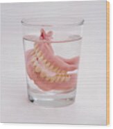 False teeth in glass of water, close-up Wood Print