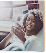 Happy Woman Using Mobile Phone On Sofa Wood Print