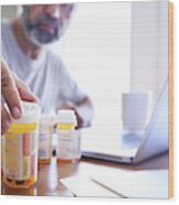 Hispanic Man Sitting At Dining Room Table Reaches For His Prescription Medications Wood Print