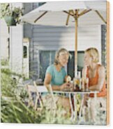 Senior Woman And Young Woman Drinking Ice Tea Out On Porch Wood Print