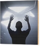Silhouette Of A Man With Raised Hands Against Light Coming From Above. Wood Print