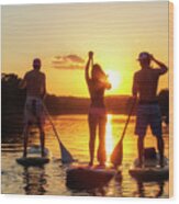 A Group Of Friends, Silhouetted By The Sunset, Exercise On Stand-up Paddle Boards On Lady Bird Lake In Austin, Texas Wood Print