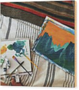 High Angle View Of Paintings With Paint Tubes And Paintbrushes On Bed In Motor Home Wood Print