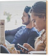 Hispanic Couple With Newspaper And Cell Phone In Coffee Shop Wood Print
