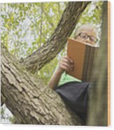 Low Angle View Of Caucasian Boy Reading In Tree Wood Print