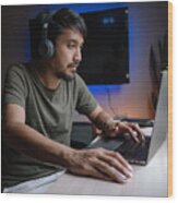 Millennial man playing computer game on laptop at home. Wood Print