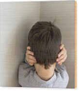 Mixed Race boy standing in corner covering ears Wood Print
