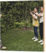 Mixed-race Sisters Being Filmed By Mother In Backyard. Wood Print