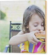 Preschool Girl Eating Messy Cheeseburger On Patio Wood Print