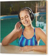 Relaxed Smiling Woman Listening To Music In Headphones Bathing In Swimming Pool. Blonde Girl Enjoys Favourite Song With Goosebumps On Skin. Waterproof Headphones With Touch Control Mobility Concept Wood Print