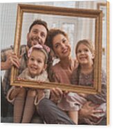 Smiling Family Having Fun With A Picture Frame At Home. Wood Print