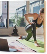 Woman Exercising At Home In Front Of Her Laptop, Stretching Her Legs Wood Print