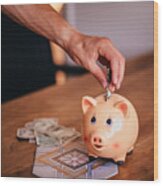 Young Man Saving Money In A Piggy Bank At Home Wood Print