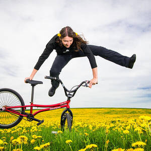 Spring has sprung - BMX Flatland artist Monika Hinz jumping in yellow flower meadow by Matthias Hauser