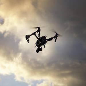 Low Angle View Of Quadcopter Flying Against Cloudy Sky by Cavan Images