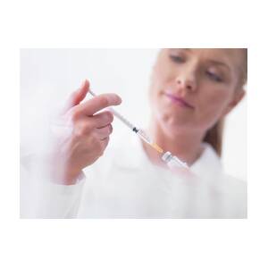Doctor holding syringe and cotton ball to prepare injections for