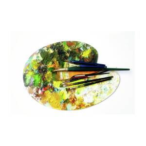 Paint brushes to the painting palette with colors on a white